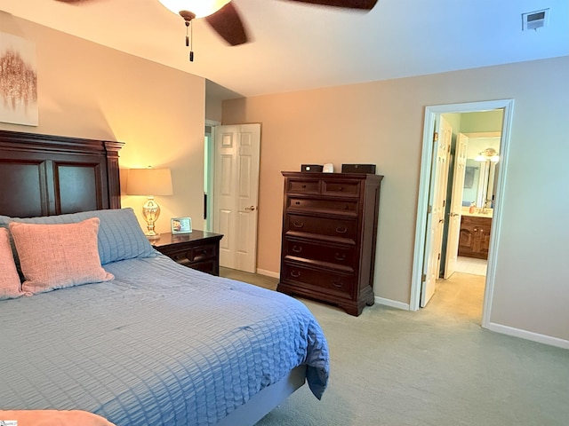bedroom with visible vents, baseboards, light carpet, a ceiling fan, and ensuite bath