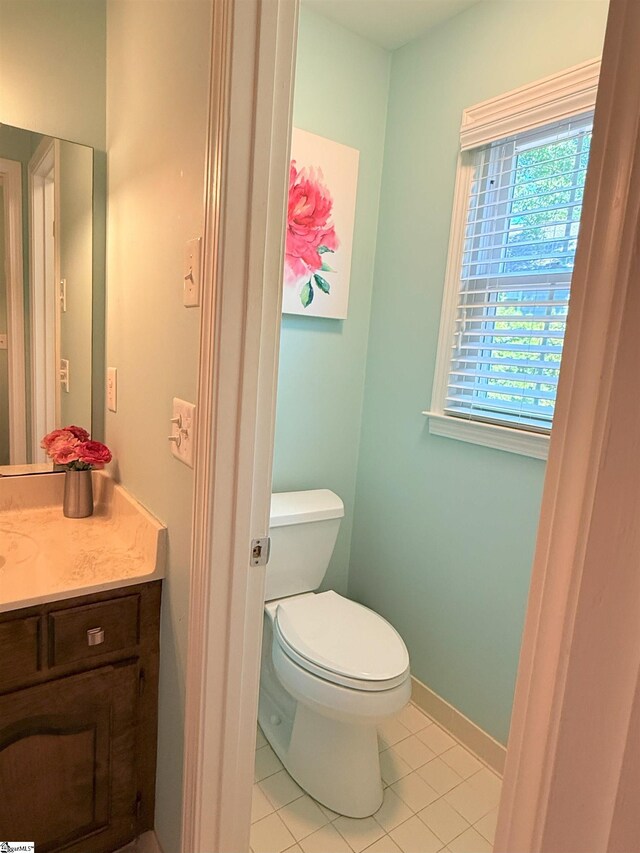bathroom featuring toilet, vanity, tile patterned flooring, and baseboards