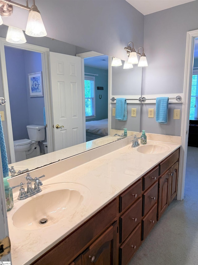 full bath featuring double vanity, toilet, ensuite bathroom, and a sink