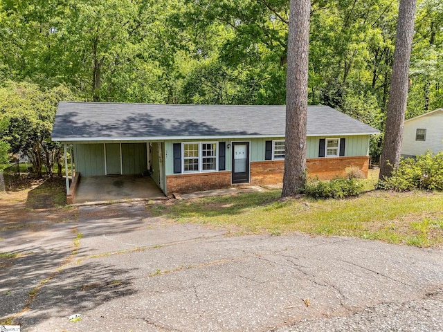 ranch-style home featuring a carport, roof with shingles, aphalt driveway, and brick siding