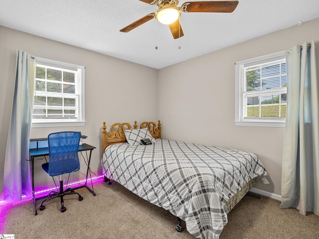 carpeted bedroom featuring a ceiling fan, multiple windows, and baseboards