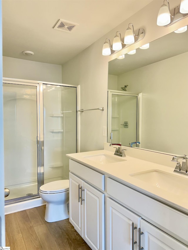 full bath with a sink, a shower stall, and wood finished floors