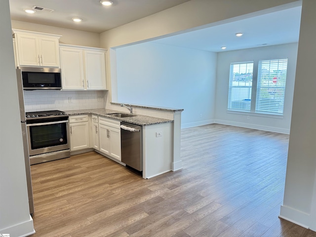 kitchen with light wood finished floors, light stone countertops, a sink, visible vents, and appliances with stainless steel finishes