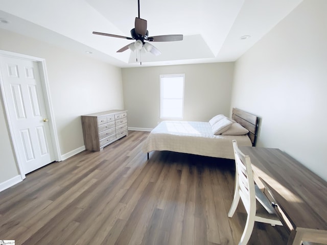 bedroom featuring a ceiling fan, a raised ceiling, wood finished floors, and baseboards