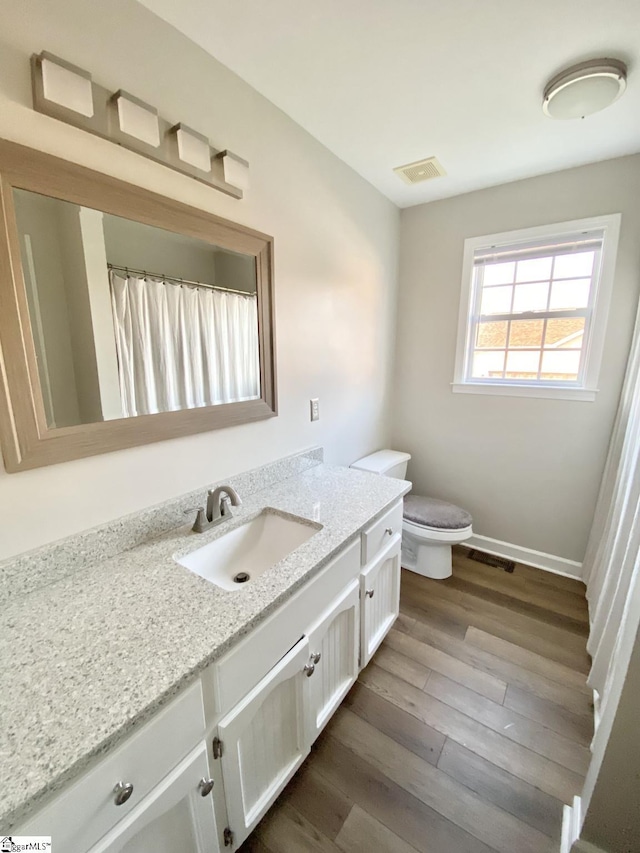bathroom with visible vents, wood finished floors, toilet, and vanity