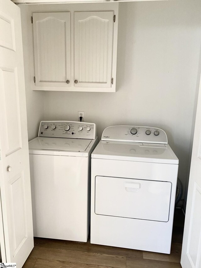 washroom with cabinet space, dark wood-style floors, and washing machine and dryer