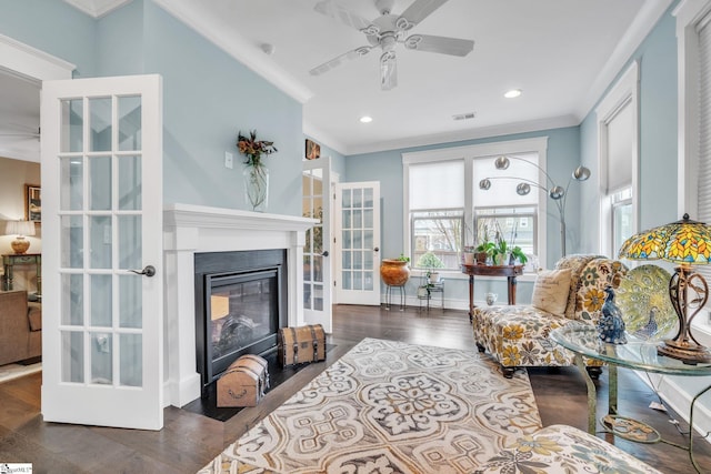 living room featuring ornamental molding, a ceiling fan, and a glass covered fireplace