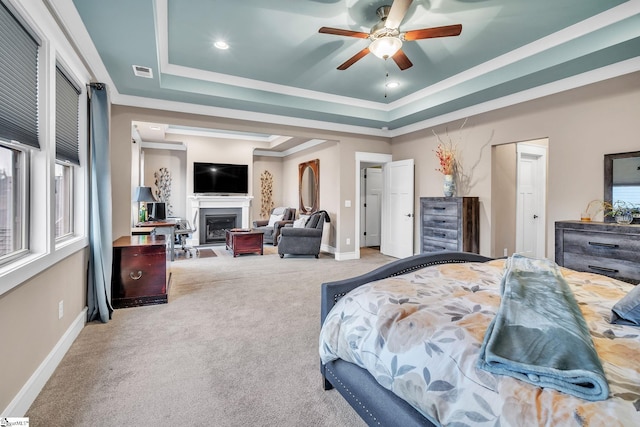 carpeted bedroom with a fireplace, a tray ceiling, crown molding, visible vents, and baseboards