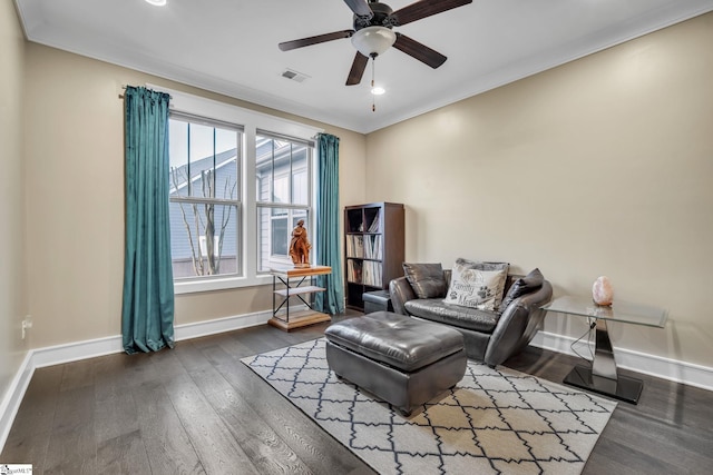 living area with ornamental molding, wood finished floors, visible vents, and baseboards