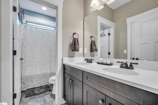 full bathroom with double vanity, toilet, and a sink