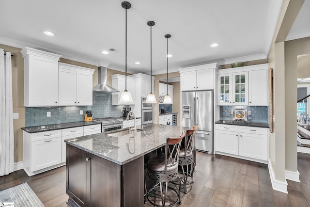 kitchen featuring wall chimney range hood, stainless steel appliances, dark wood-style floors, and a sink