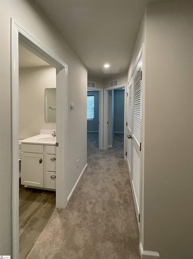 corridor featuring visible vents, baseboards, and carpet floors
