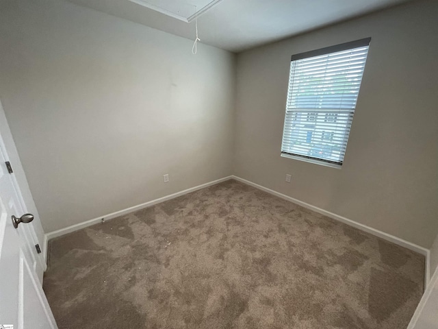 carpeted spare room with baseboards and attic access
