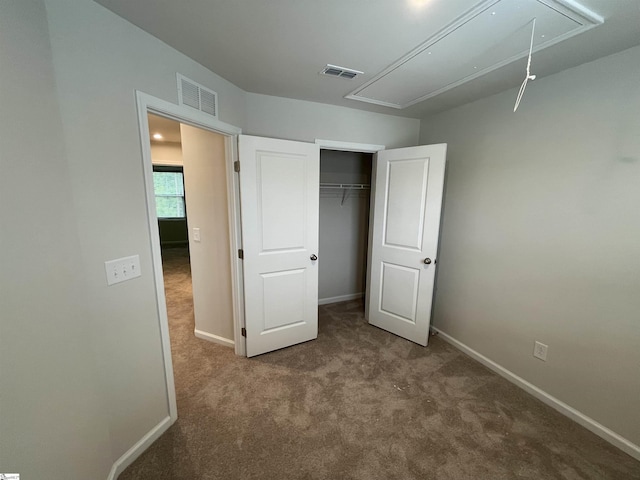 unfurnished bedroom with attic access, visible vents, baseboards, and carpet floors