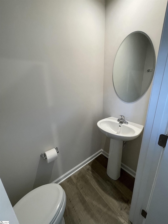 bathroom featuring toilet, a sink, wood finished floors, and baseboards