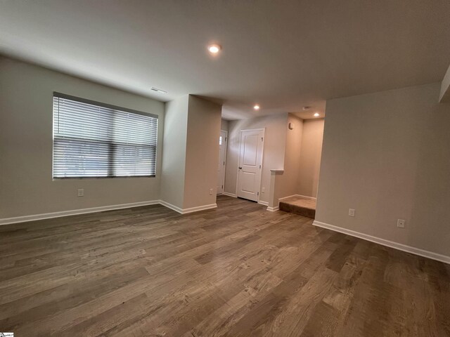 spare room featuring recessed lighting, dark wood-style flooring, and baseboards