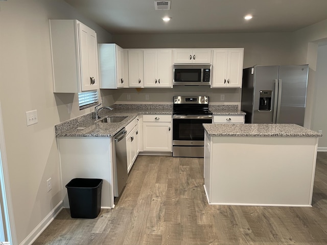 kitchen with stainless steel appliances, wood finished floors, and a sink