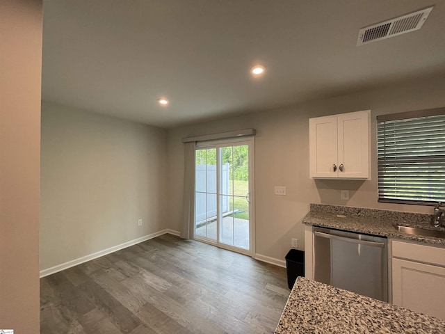 kitchen featuring white cabinetry, stainless steel dishwasher, a sink, visible vents, and wood finished floors