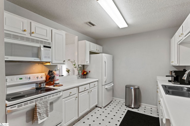 kitchen featuring visible vents, white appliances, white cabinets, and a sink