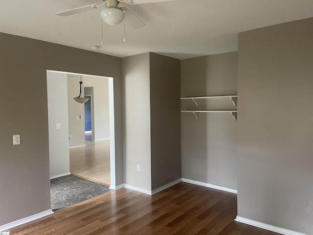 unfurnished bedroom with wood finished floors, a closet, ceiling fan, baseboards, and a textured ceiling