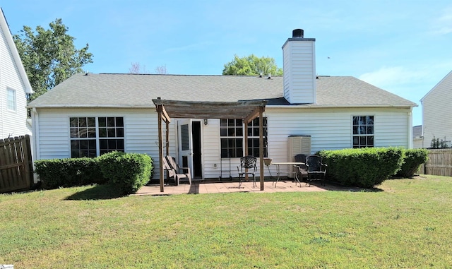 rear view of property featuring a chimney, fence, a pergola, a patio area, and a lawn
