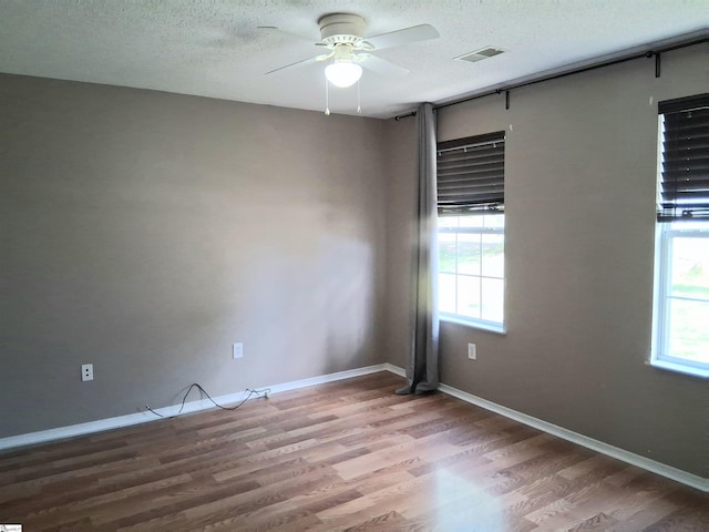 unfurnished room featuring visible vents, ceiling fan, wood finished floors, and a healthy amount of sunlight