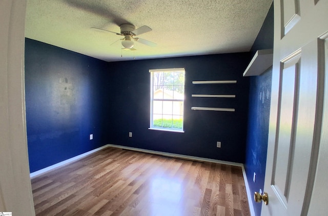 spare room with wood finished floors, a ceiling fan, and a textured ceiling