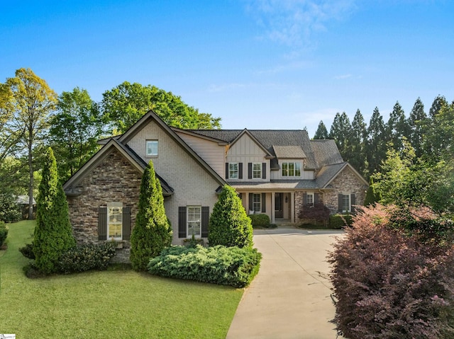 view of front of house with board and batten siding, a front lawn, driveway, and stone siding