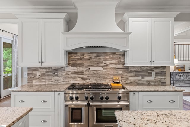 kitchen featuring range with two ovens, ornamental molding, premium range hood, and white cabinetry