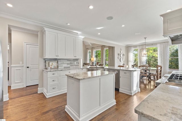 kitchen featuring a sink, appliances with stainless steel finishes, ornamental molding, wood finished floors, and a peninsula