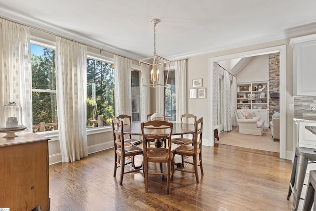 dining room with baseboards, wood finished floors, a notable chandelier, and lofted ceiling