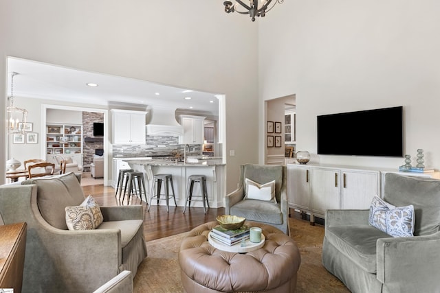 living room featuring recessed lighting, a high ceiling, an inviting chandelier, and light wood-style floors
