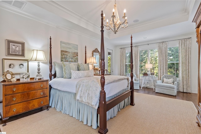 bedroom featuring crown molding, a chandelier, visible vents, a tray ceiling, and wood finished floors