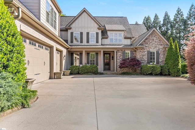 view of front of property with board and batten siding, a shingled roof, driveway, stone siding, and an attached garage