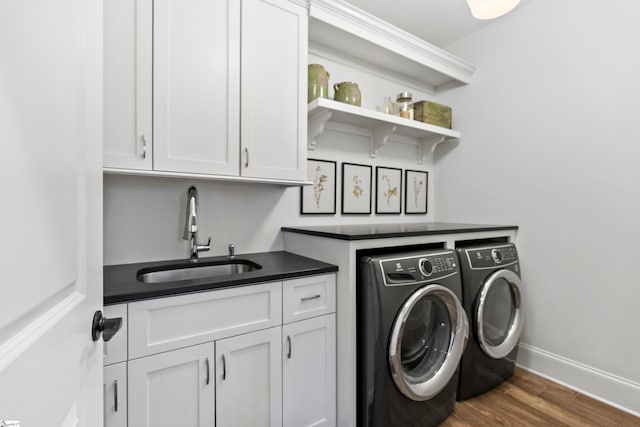 washroom with cabinet space, a sink, independent washer and dryer, baseboards, and wood finished floors