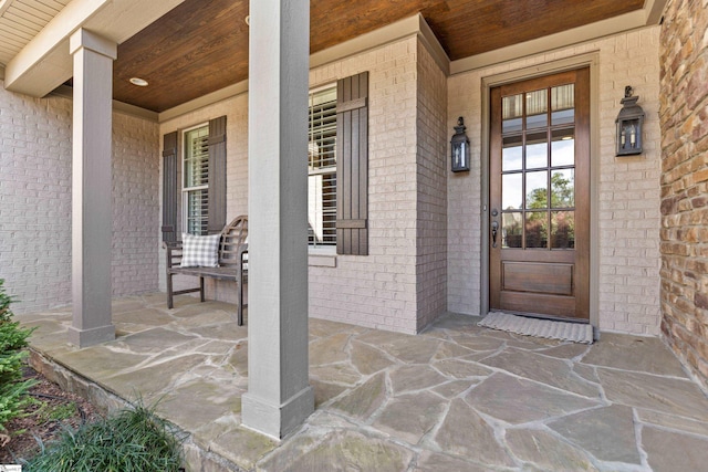 entrance to property featuring brick siding and a porch