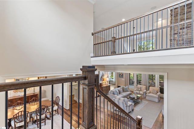 stairway with wood finished floors and a towering ceiling