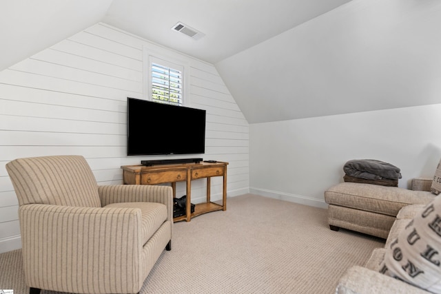 living room with light colored carpet, vaulted ceiling, baseboards, visible vents, and wooden walls