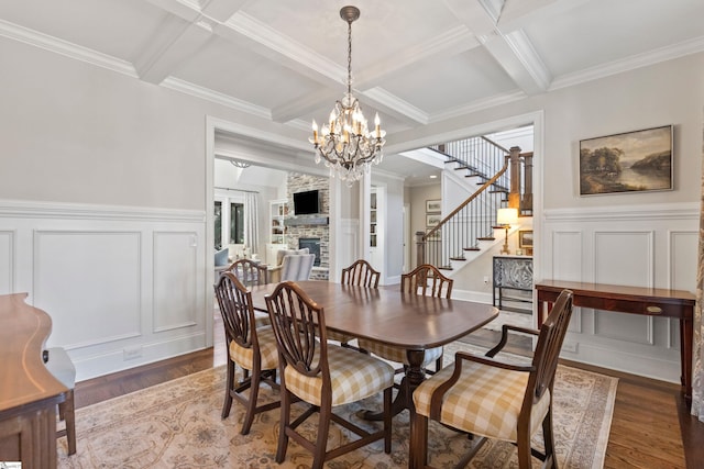 dining area with an inviting chandelier, stairway, beam ceiling, coffered ceiling, and a decorative wall