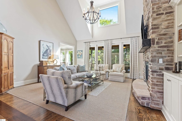 living room with a notable chandelier, baseboards, a fireplace, wood finished floors, and high vaulted ceiling
