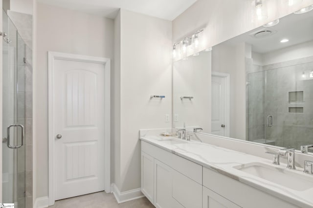 full bath with a stall shower, double vanity, a sink, and baseboards