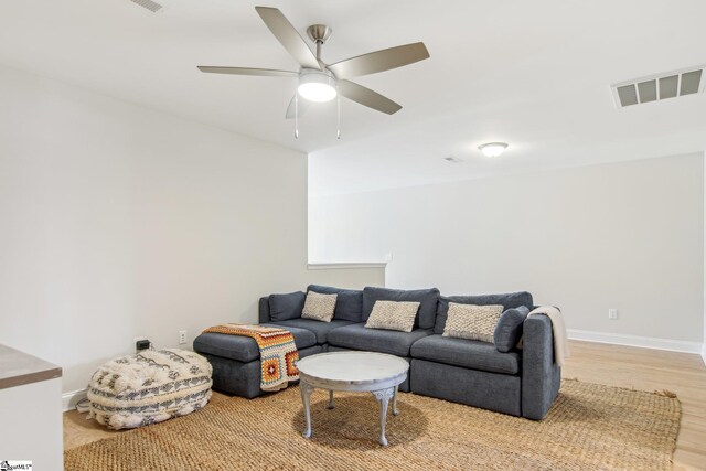 living area featuring ceiling fan, visible vents, light wood-type flooring, and baseboards