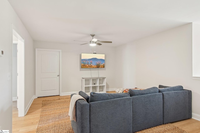 living area featuring baseboards, a ceiling fan, and light wood-style floors