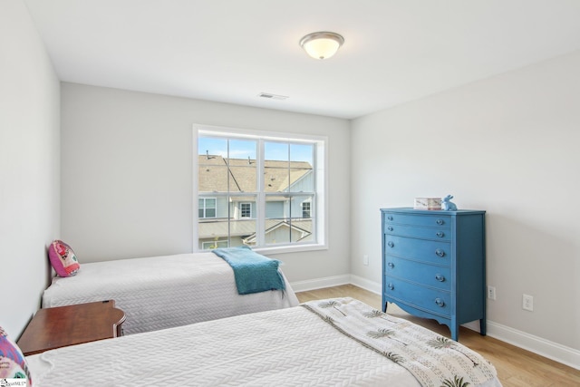 bedroom featuring light wood-type flooring, visible vents, and baseboards
