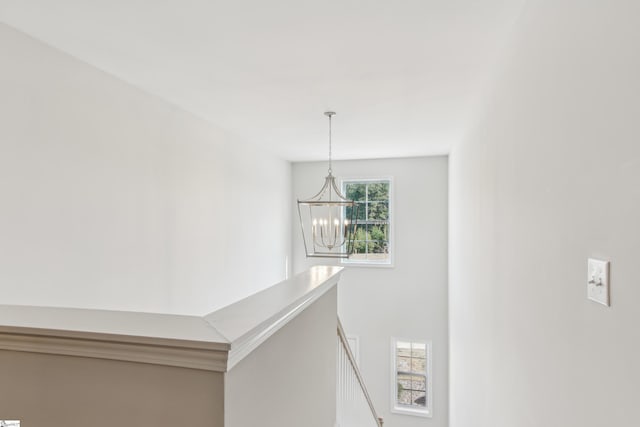 hall featuring an upstairs landing and a notable chandelier