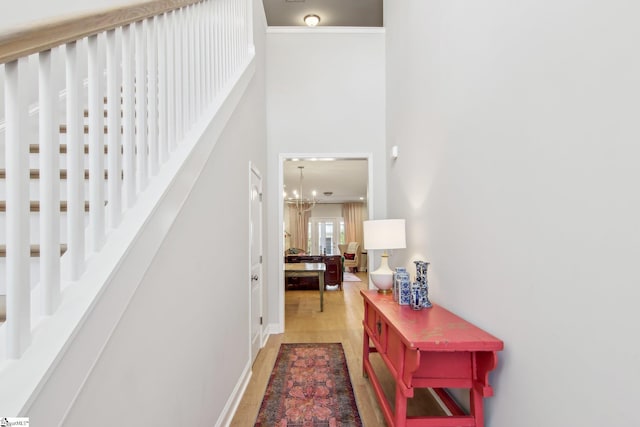 corridor with a chandelier, light wood finished floors, and a towering ceiling