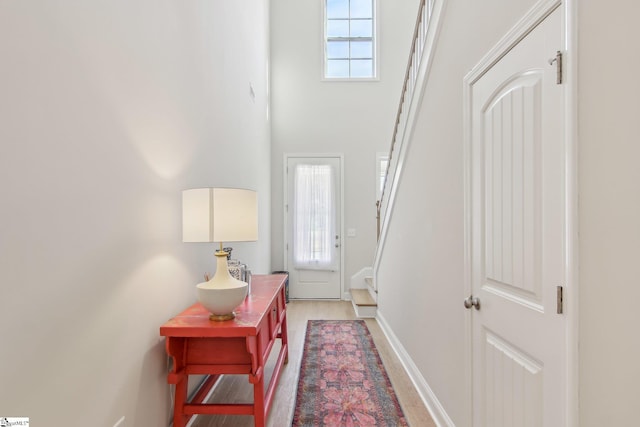 foyer with a high ceiling, baseboards, stairs, and light wood-type flooring
