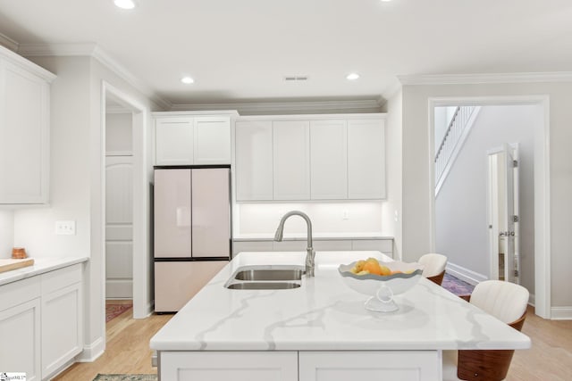 kitchen with crown molding, white cabinets, light wood-style flooring, a sink, and freestanding refrigerator