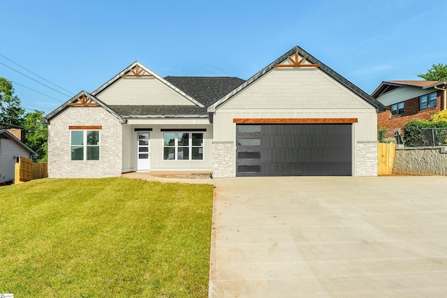 view of front facade featuring a front yard, a garage, driveway, stone siding, and fence