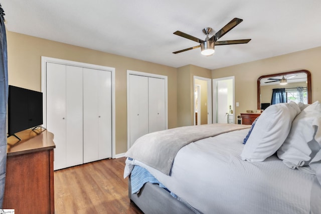bedroom featuring ceiling fan, light wood-style flooring, and multiple closets
